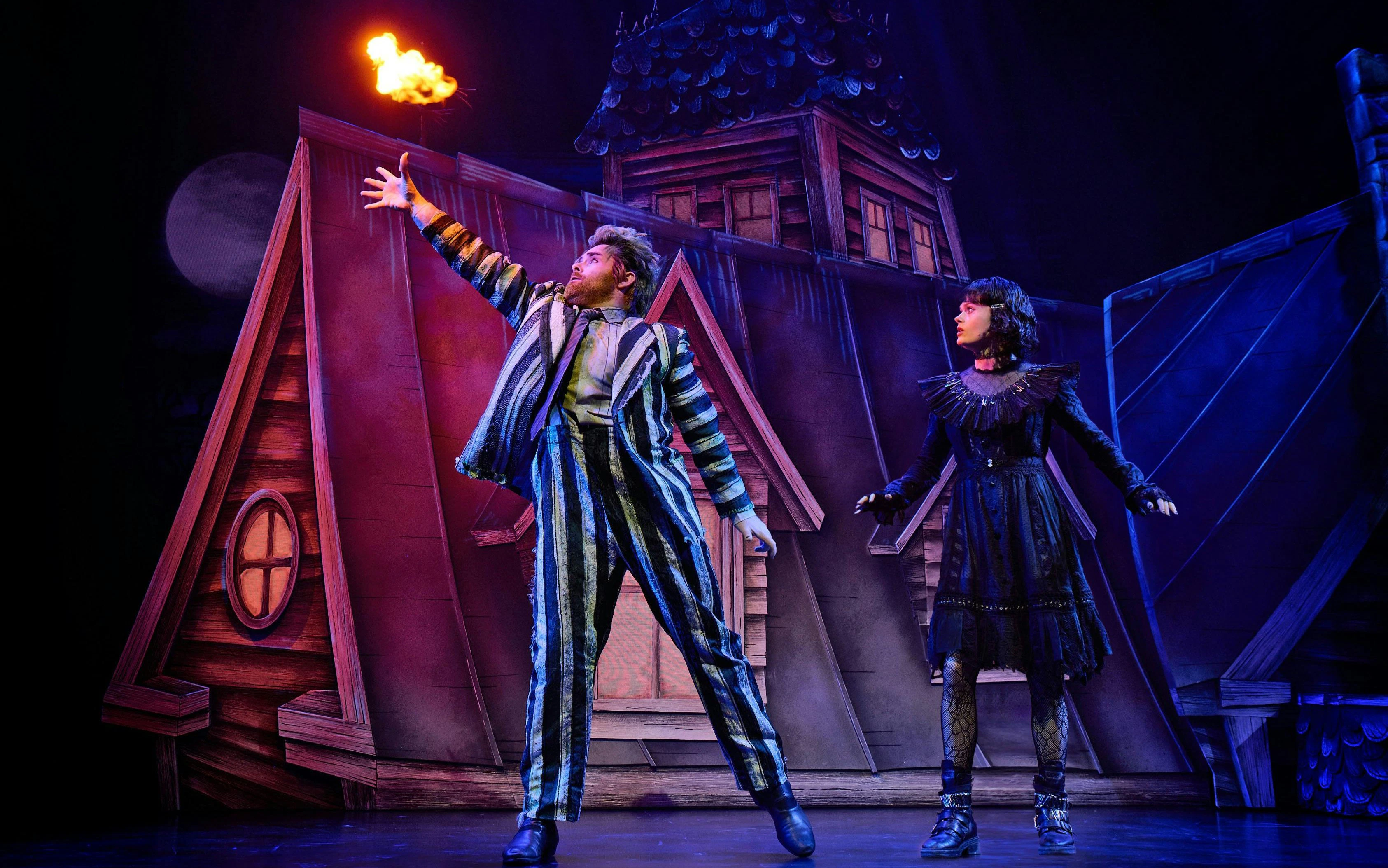 Beetlejuice character on West End stage with gothic house backdrop.