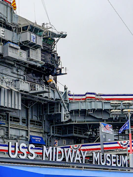 USS Midway Museum aircraft carrier exterior with flags and signage.
