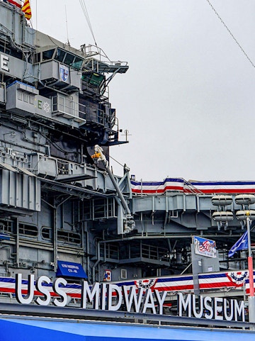 USS Midway Museum aircraft carrier exterior with flags and signage.