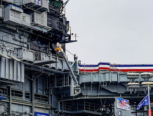 USS Midway Museum aircraft carrier exterior with flags and signage.