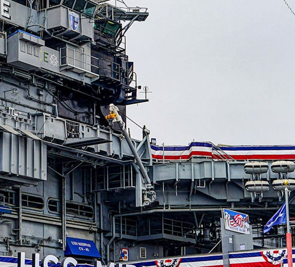 USS Midway Museum aircraft carrier exterior with flags and signage.