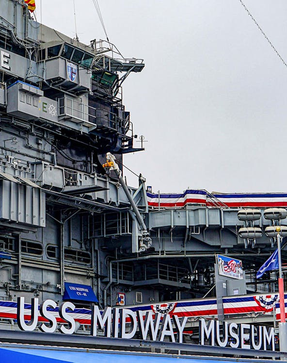 USS Midway Museum aircraft carrier exterior with flags and signage.