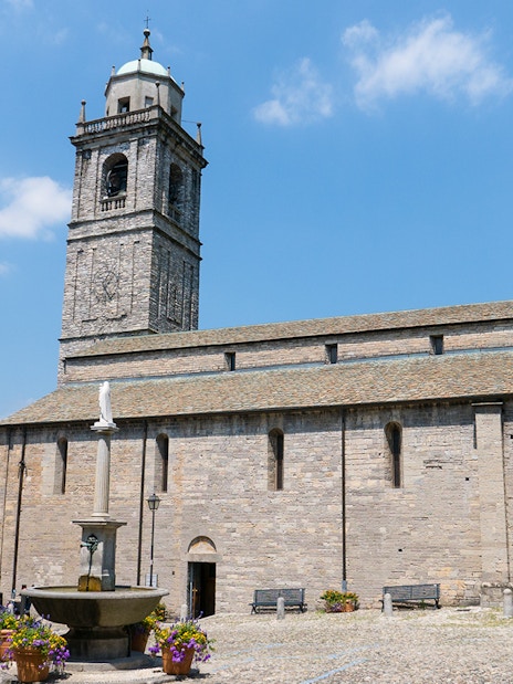Basilica di San Giacomo in Bellagio with a fountain and Lake Como in the background.