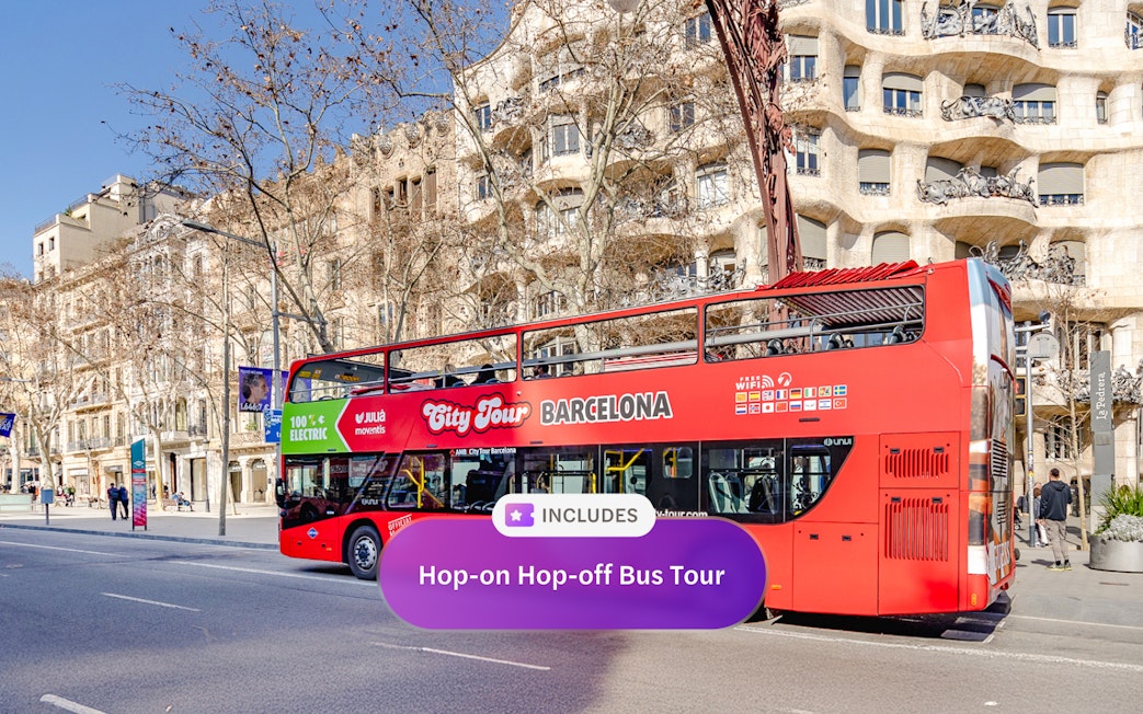 Red double-decker bus on a hop-on hop-off tour in front of Casa Milà, Barcelona.