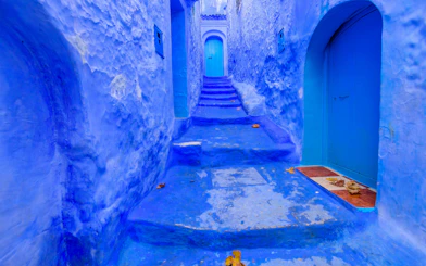 Blue alleyway in Chefchaouen, Morocco with vibrant painted walls and steps.