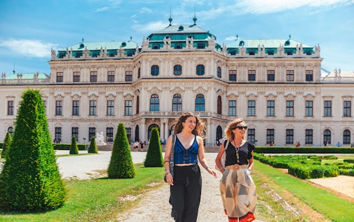Tourists walking on the lawn of Upper Belvedere Palace in Vienna.
