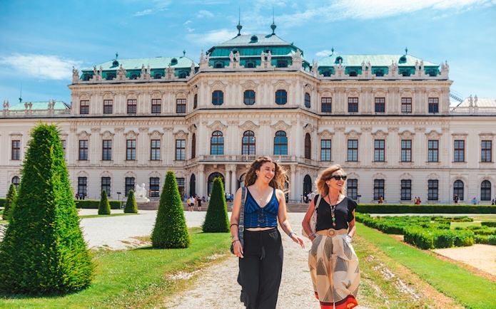 Tourists walking on the lawn of Upper Belvedere Palace in Vienna.
