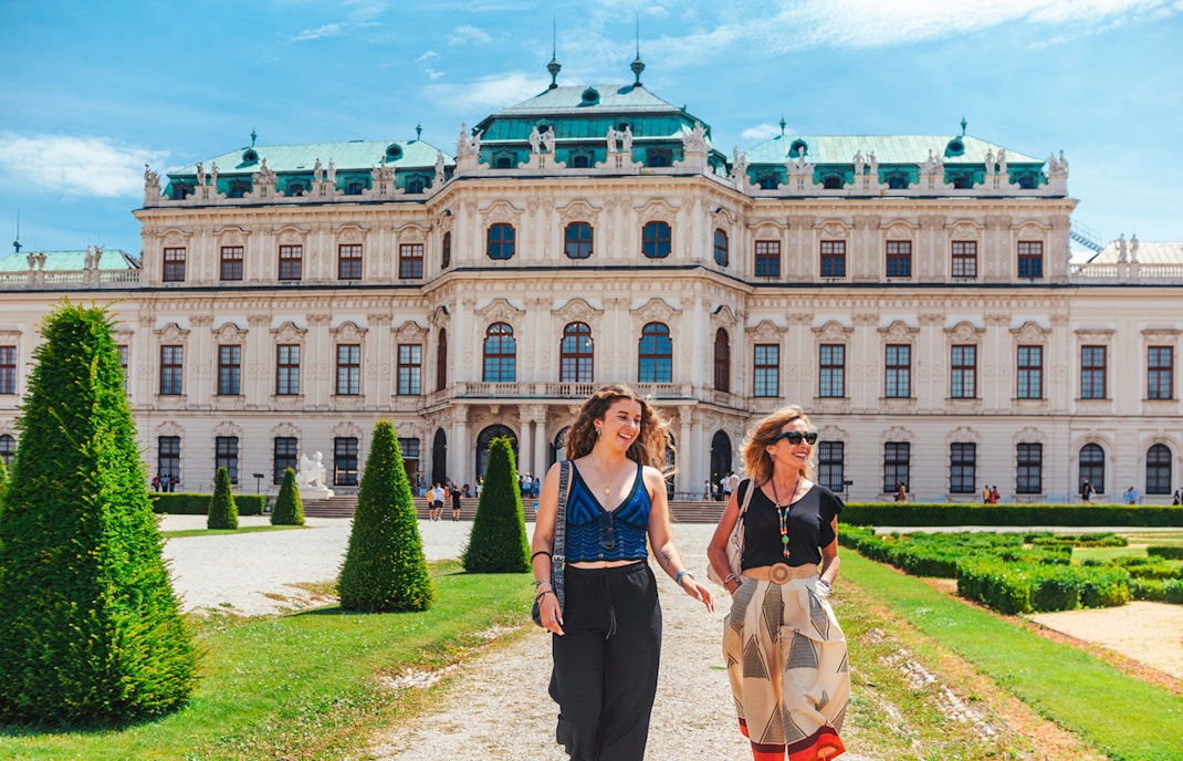 Tourists walking on the lawn of Upper Belvedere Palace in Vienna.