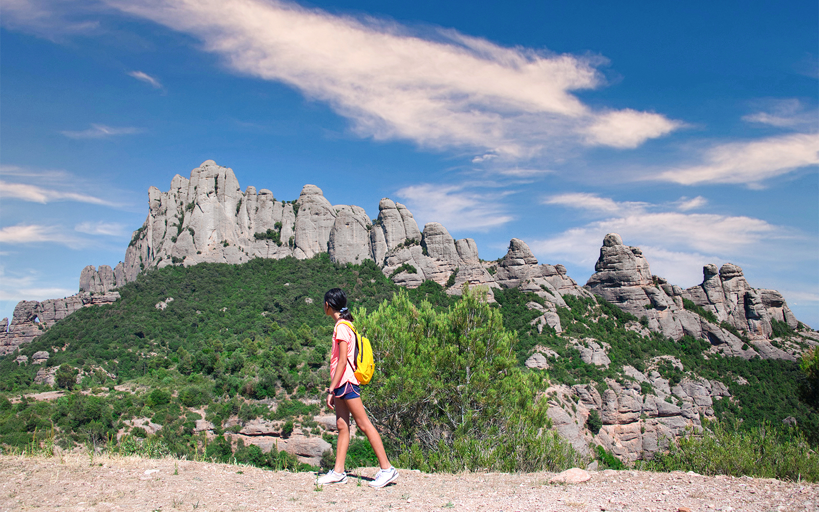 Hikers on a trail with Montserrat mountain range in the background, Spain.