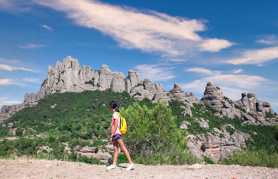 Hikers on a trail with Montserrat mountain range in the background, Spain.