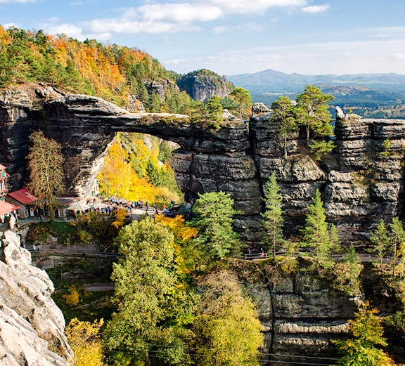 Pravčická Brána rock formation surrounded by autumn trees in Bohemian Switzerland.