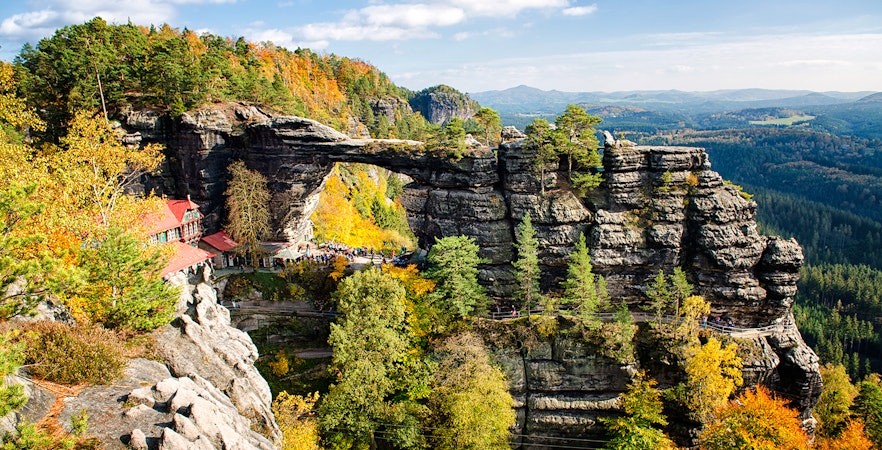 Pravčická Brána rock formation surrounded by autumn trees in Bohemian Switzerland.