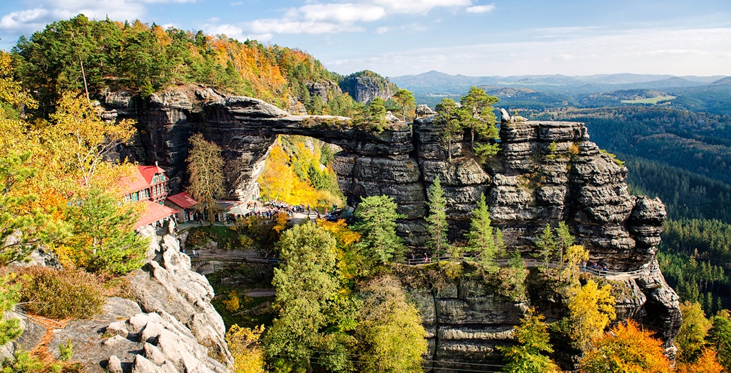 Pravčická Brána rock formation surrounded by autumn trees in Bohemian Switzerland.