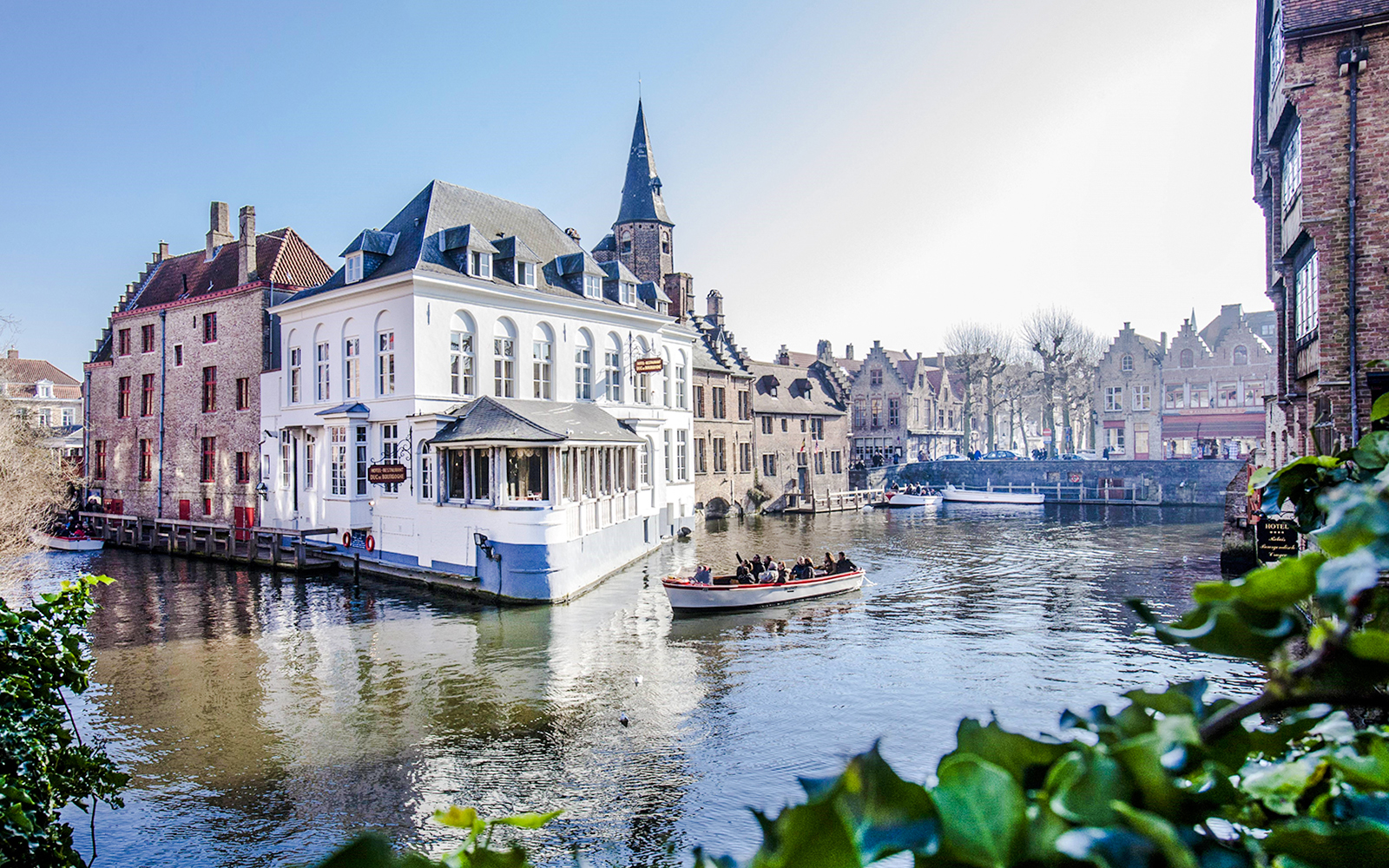 Scenic canal with boat and historic buildings in Bruges, Belgium.