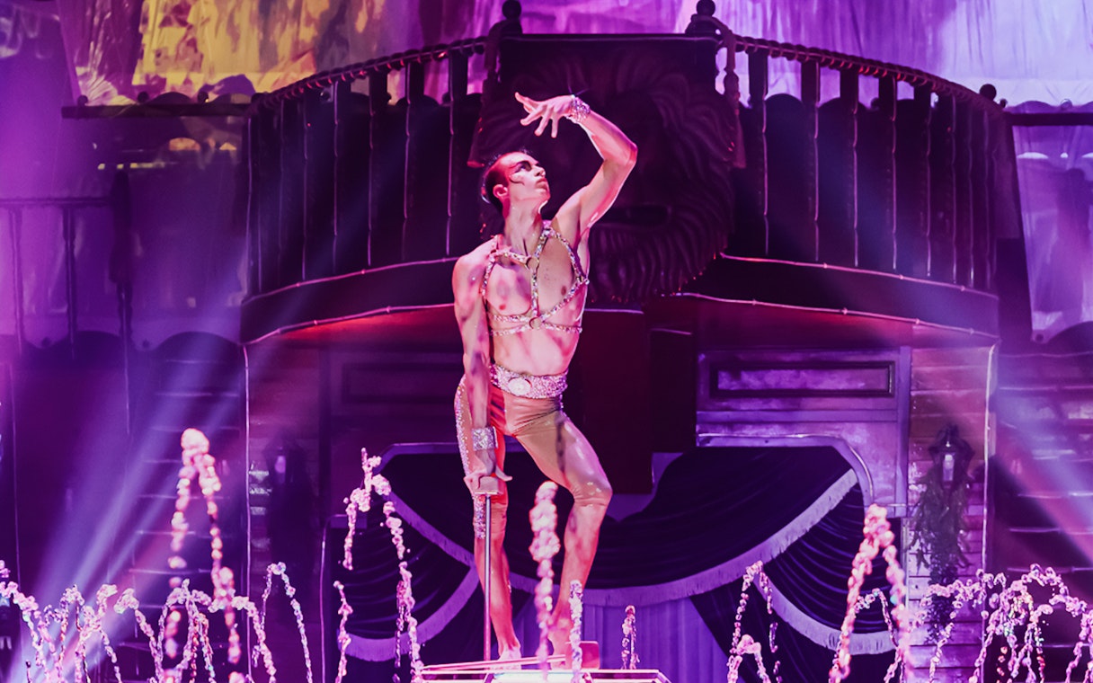 Performer on stage at Aqua Circus Phuket with water fountains and dramatic lighting.