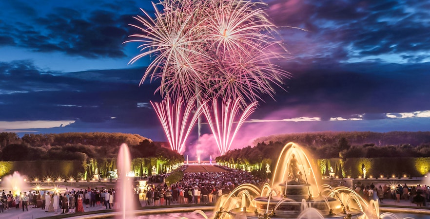 Fireworks over Versailles fountains during night show, viewed from Paris tour.