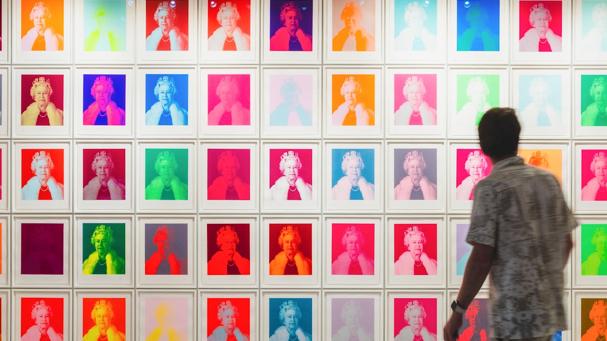 Man viewing colorful pop art portraits in a gallery.