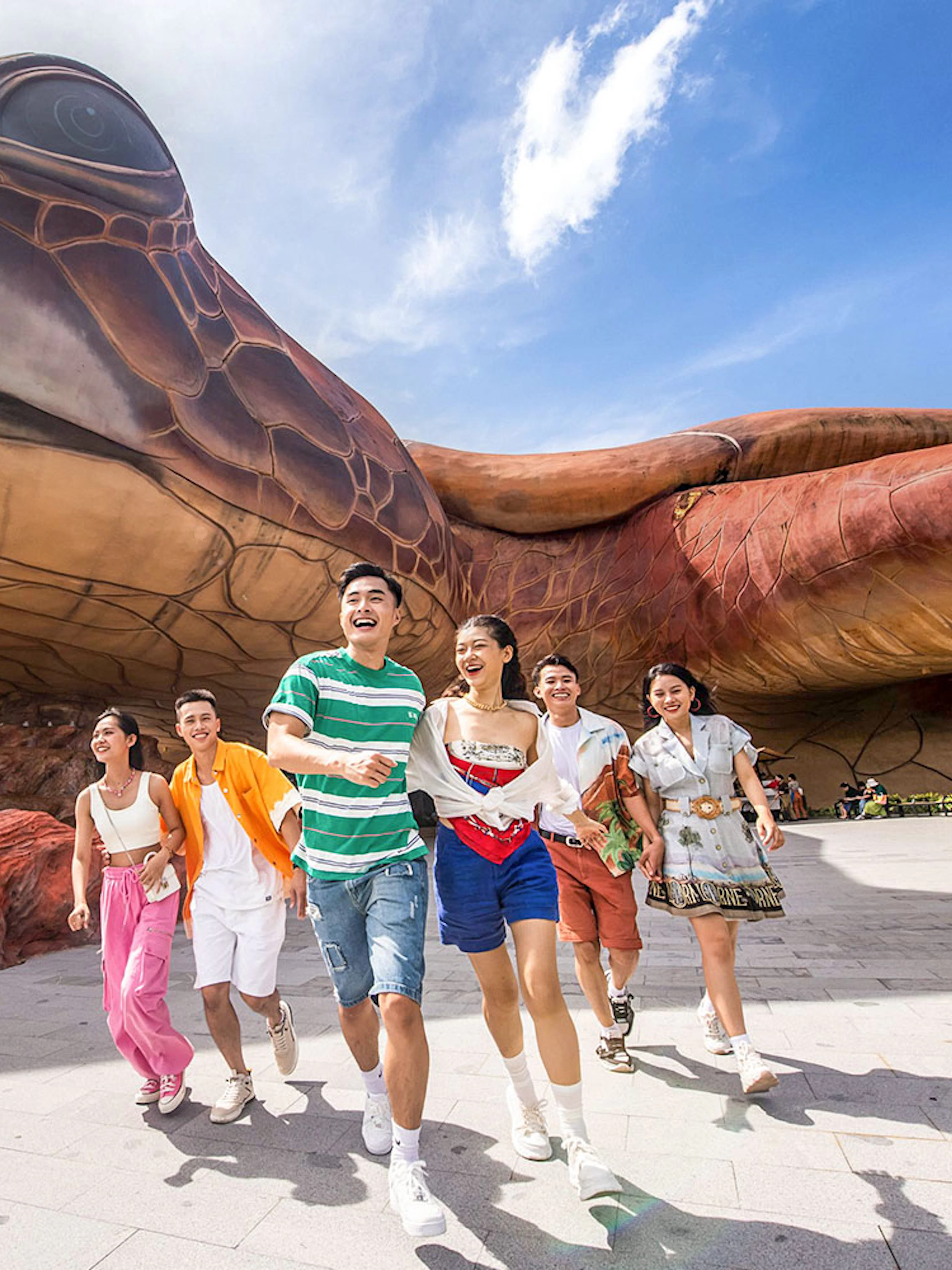 Guests enjoying VinWonders Phu Quoc near giant turtle sculpture.