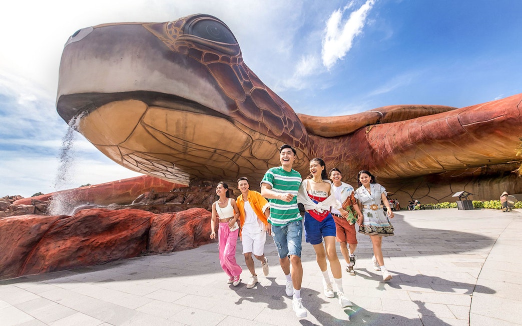 Guests enjoying VinWonders Phu Quoc near giant turtle sculpture.