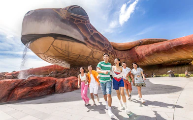 Guests enjoying VinWonders Phu Quoc near giant turtle sculpture.