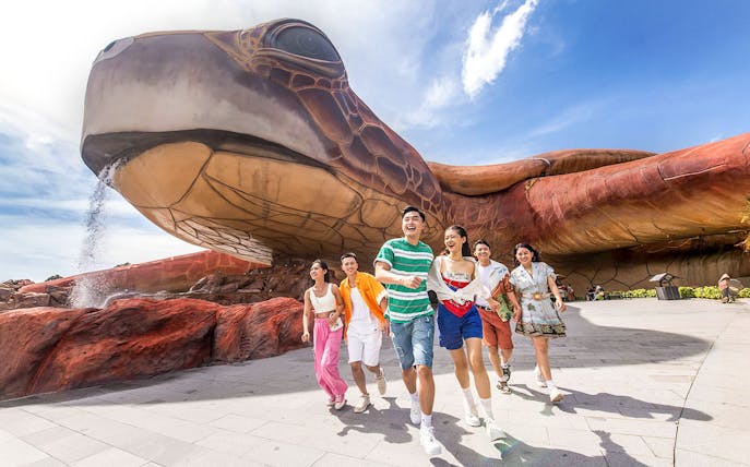 Guests enjoying VinWonders Phu Quoc near giant turtle sculpture.