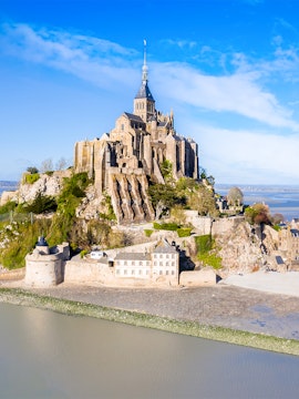Mont-Saint-Michel abbey on rocky island in Normandy, France, surrounded by water.