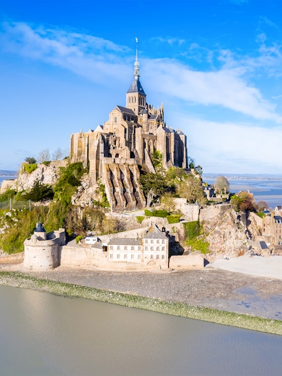 Mont-Saint-Michel abbey on rocky island in Normandy, France, surrounded by water.