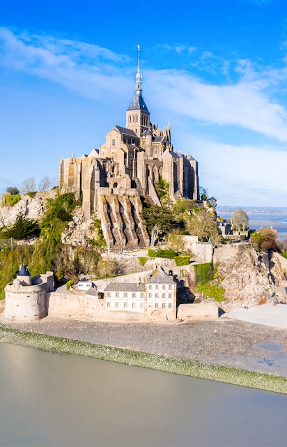 Mont-Saint-Michel abbey on rocky island in Normandy, France, surrounded by water.