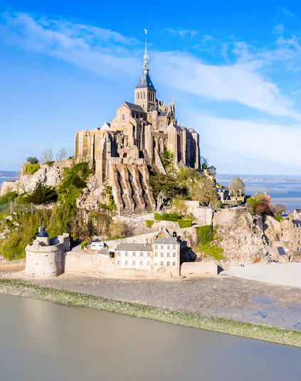 Mont-Saint-Michel abbey on rocky island in Normandy, France, surrounded by water.
