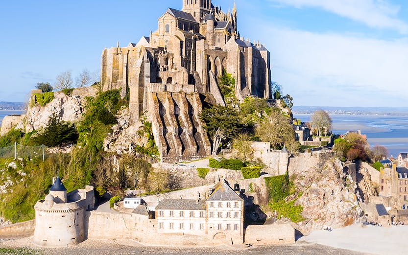 Mont-Saint-Michel abbey on rocky island in Normandy, France, surrounded by water.