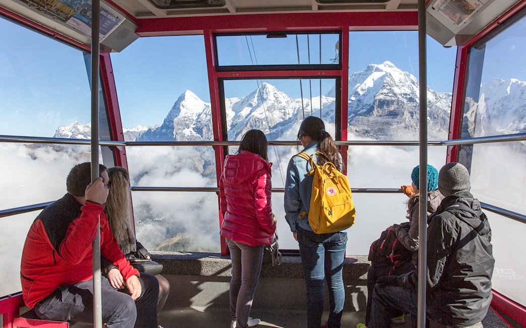 Travelers in a cable car with views of the Swiss Alps, using Swiss Travel Pass Flex.