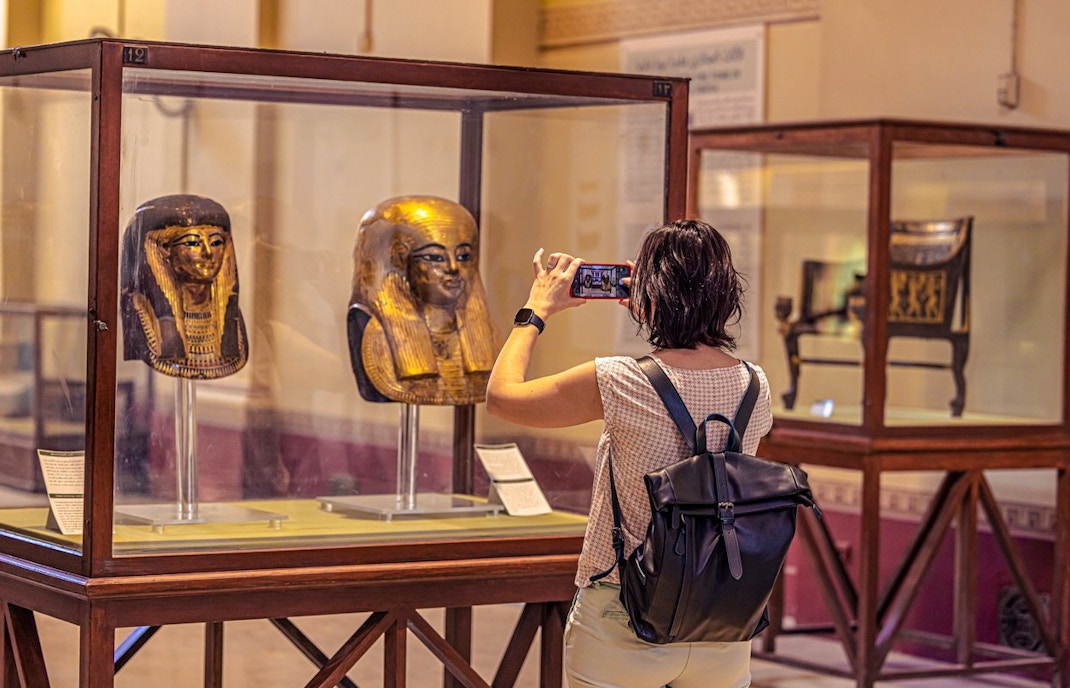 Woman taking picture of artifact at display, GEM