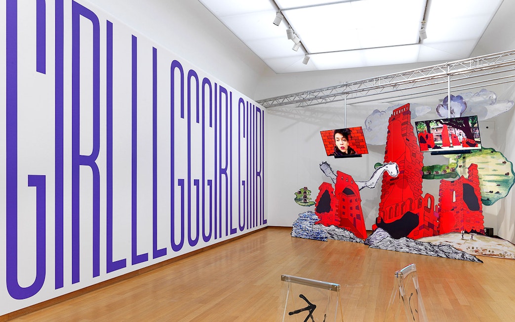 Installation view of "Tomorrow is a Different Day" at Stedelijk Museum featuring large text and red architectural structures.