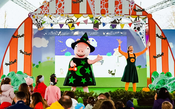 Peppa Pig in a witch costume on stage at Halloween event, PEPPA PIG Park.