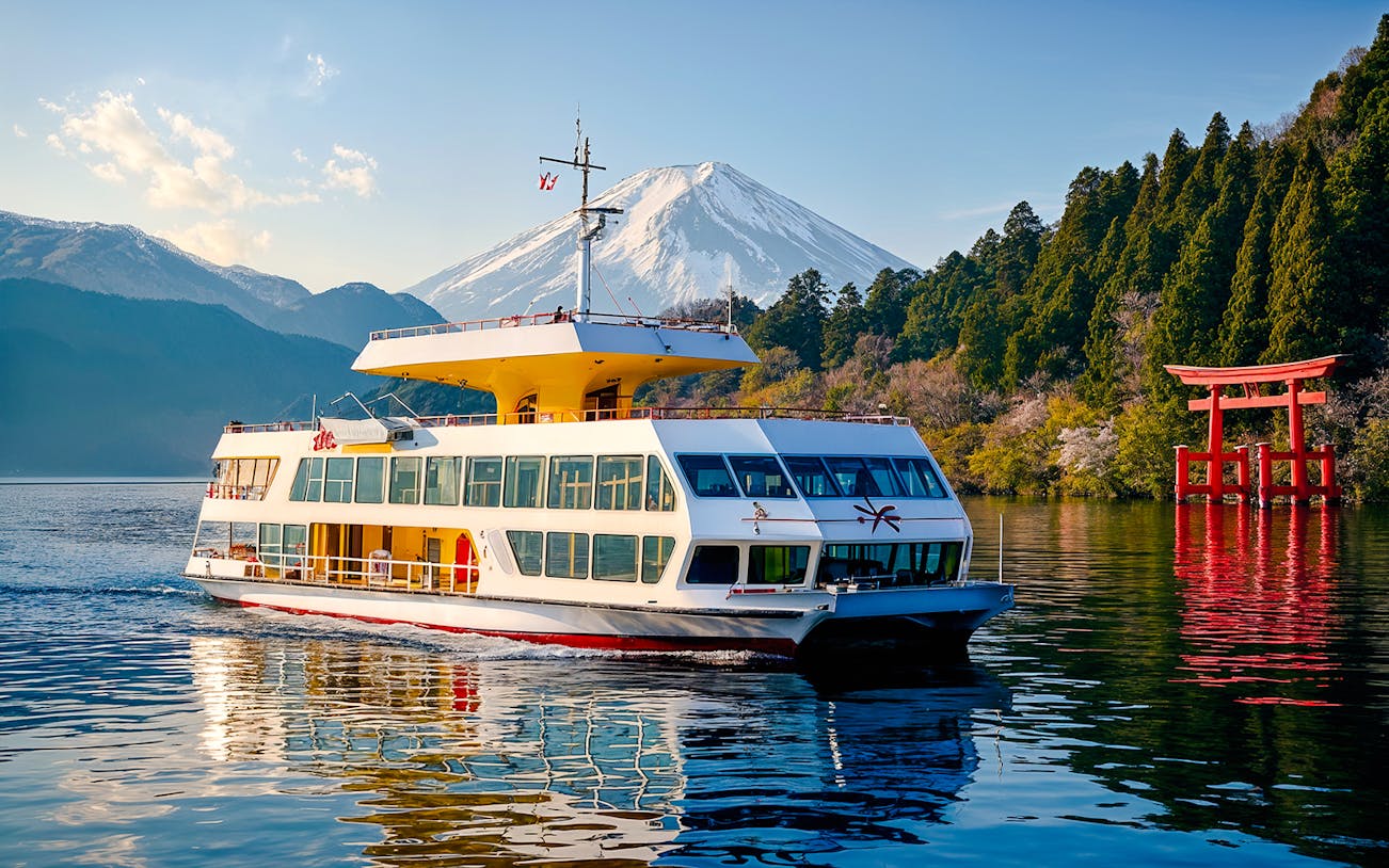 Cruise boat on Lake Ashi with Mount Fuji and torii gate in Japan.