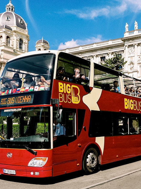 Tourists on Big Bus Vienna passing historic building on hop-on hop-off tour.