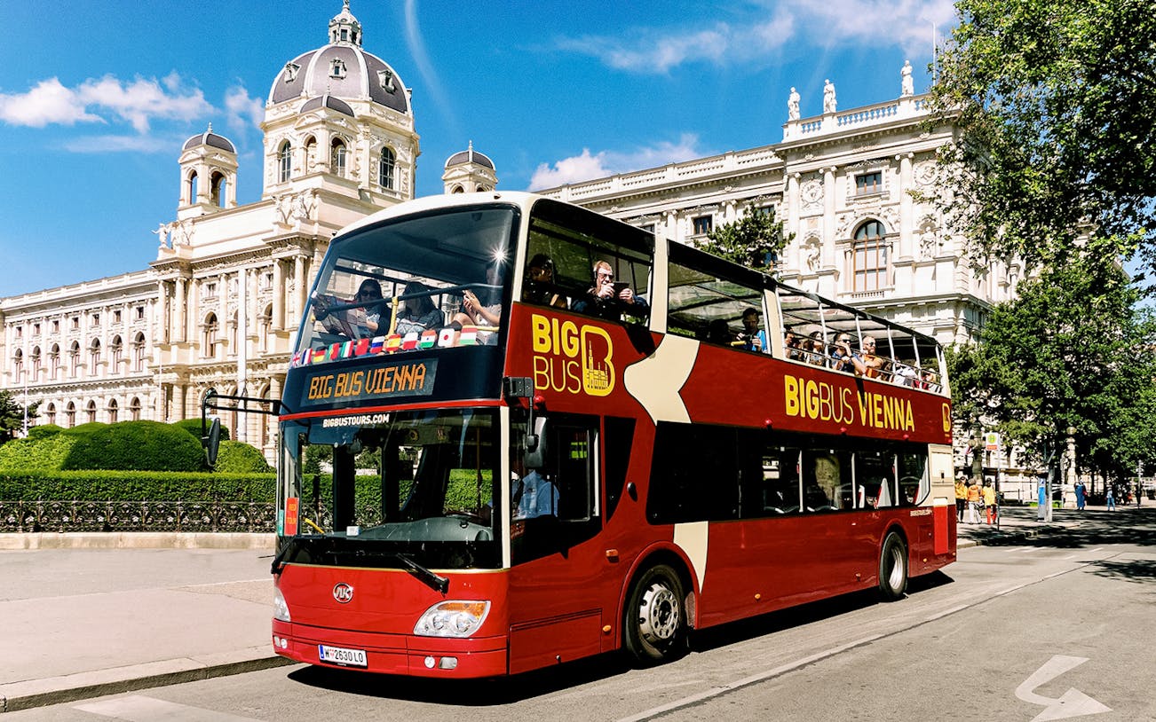 Tourists on Big Bus Vienna passing historic building on hop-on hop-off tour.