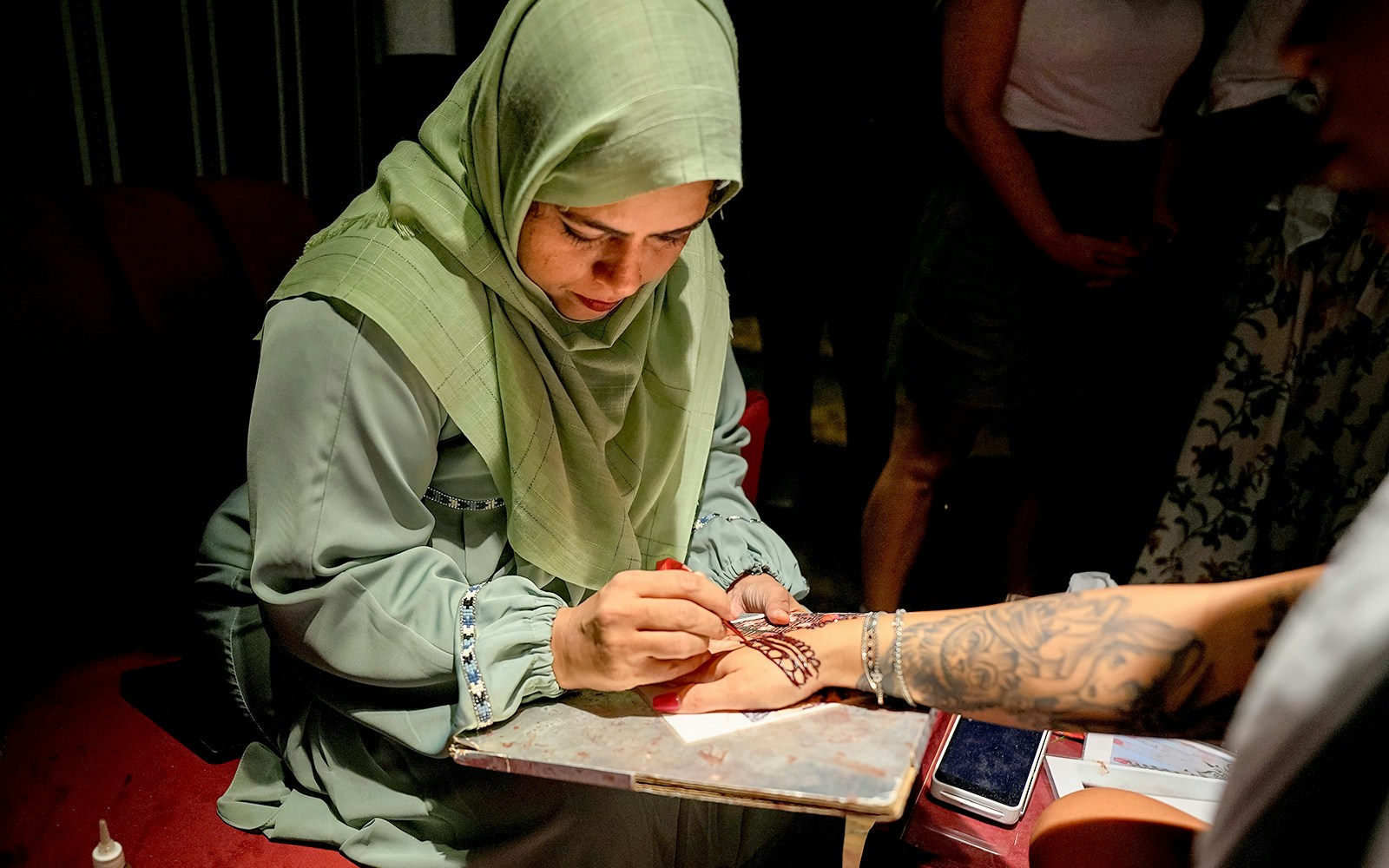 Skilled artist applying henna design on a person's hand.