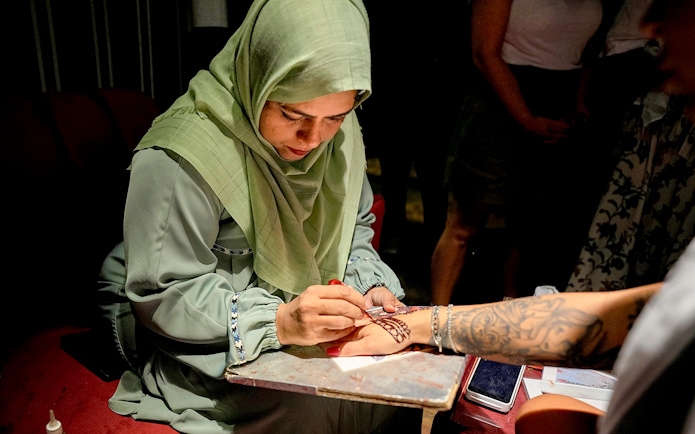 Skilled artist applying henna design on a person's hand.