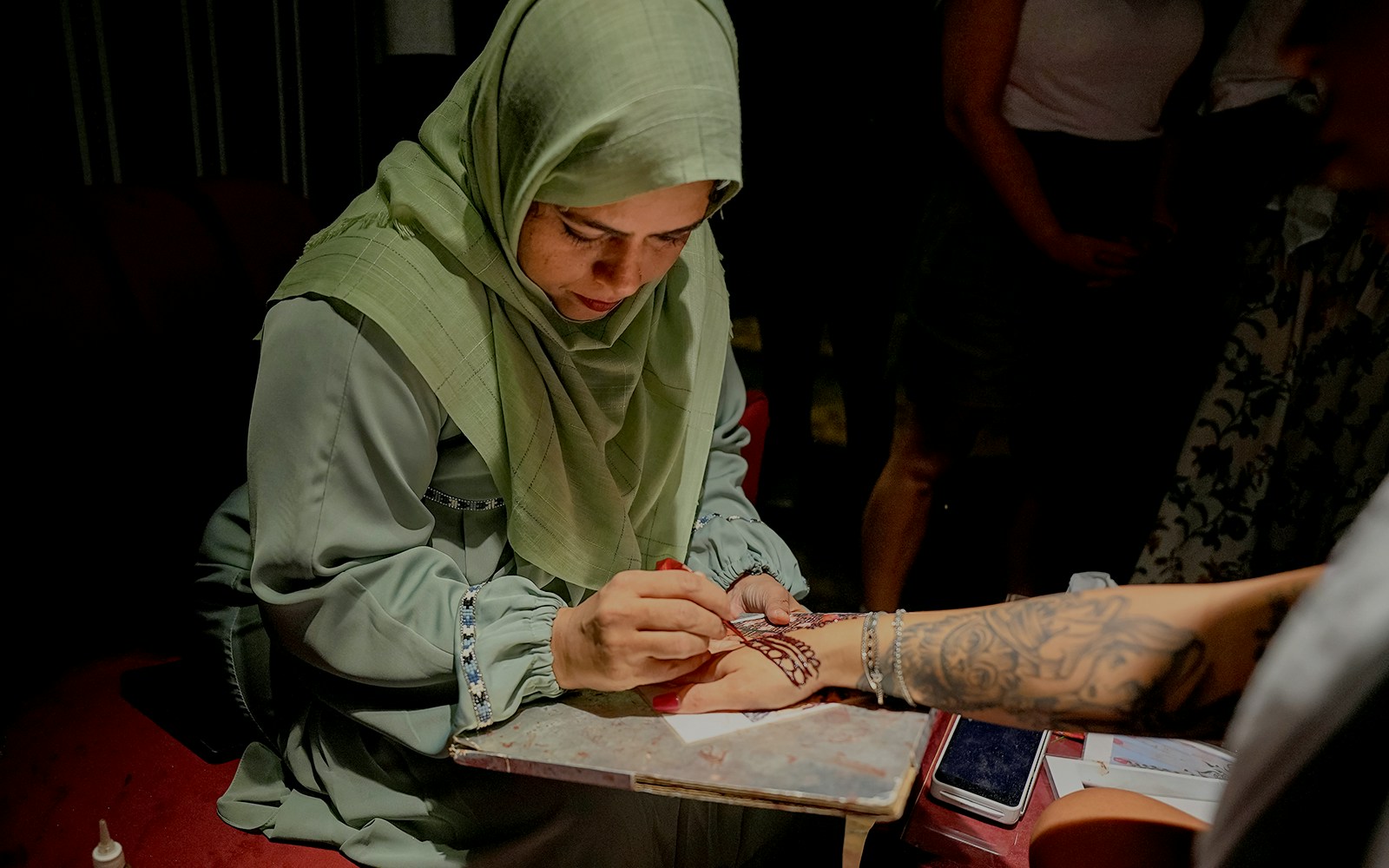 Skilled artist applying henna design on a person's hand.