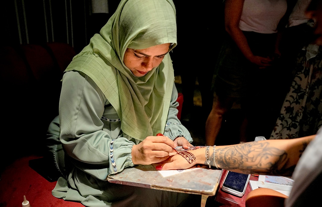 Henna artist creating intricate design on a hand during Dubai desert safari.