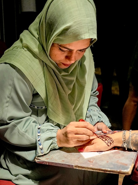 Skilled artist applying henna design on a person's hand.