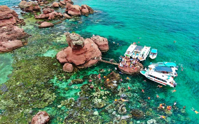 Speed boats anchored at Gam Ghi Island with tourists swimming nearby.