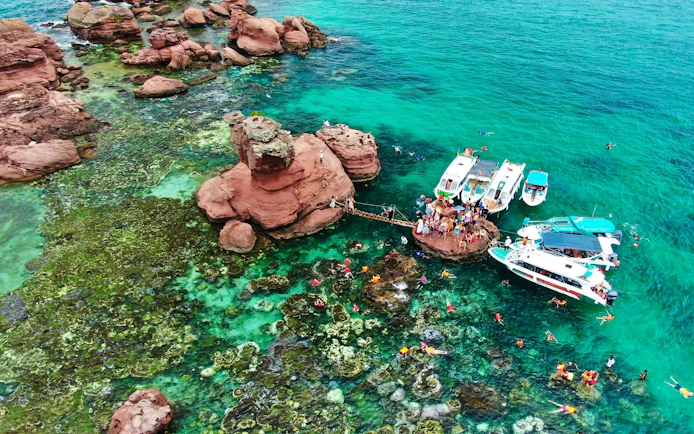 Speed boats anchored at Gam Ghi Island with tourists swimming nearby.