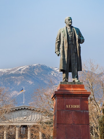 Statue of Lenin at Memento Park, Budapest with mountains in the background.
