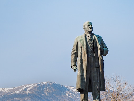 Statue of Lenin at Memento Park, Budapest with mountains in the background.