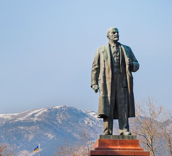 Statue of Lenin at Memento Park, Budapest with mountains in the background.
