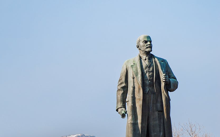 Statue of Lenin at Memento Park, Budapest with mountains in the background.