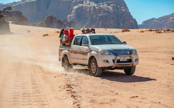 Tourists in a pickup truck exploring the desert landscape of Wadi Rum, Jordan.
