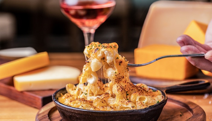 Mac and cheese dish with creamy sauce and breadcrumbs in a white bowl.